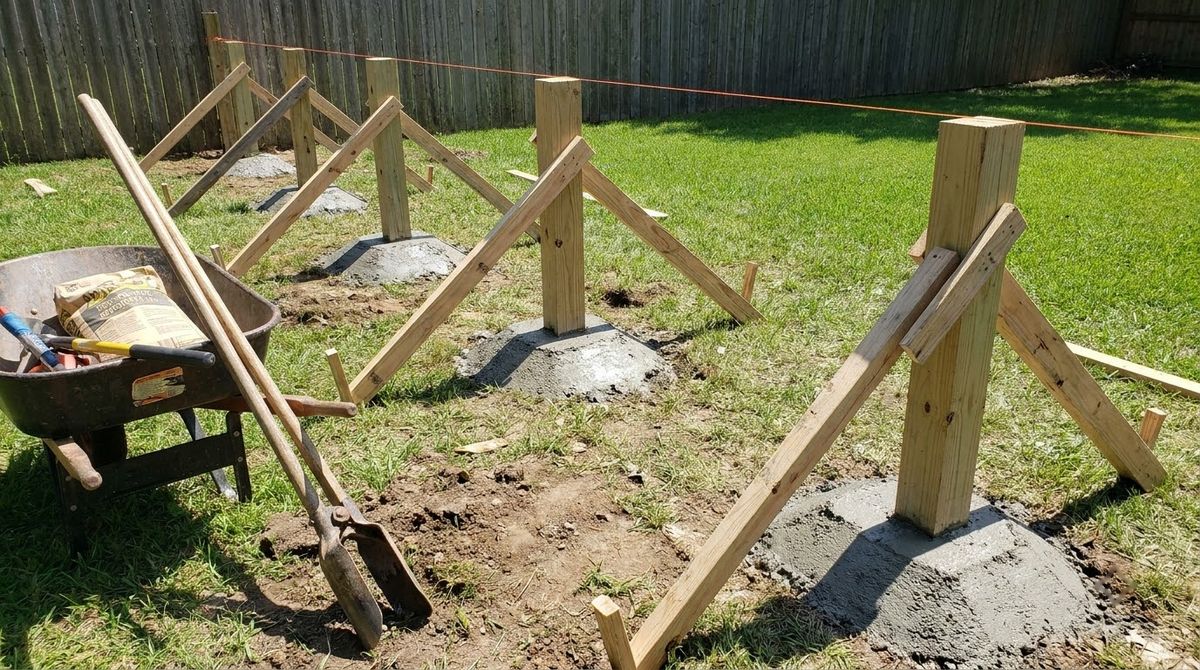 Wood fence posts set in fresh concrete along a taut mason string line in a yard