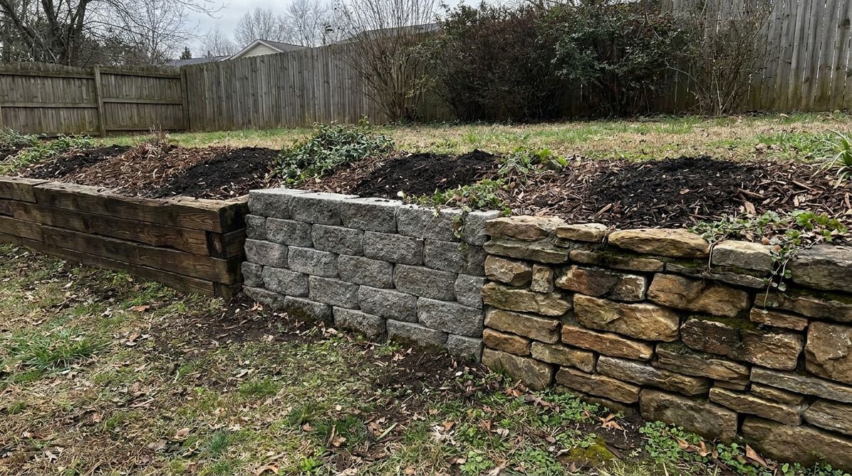 Short retaining walls in timber, concrete block and natural stone side by side in a yard