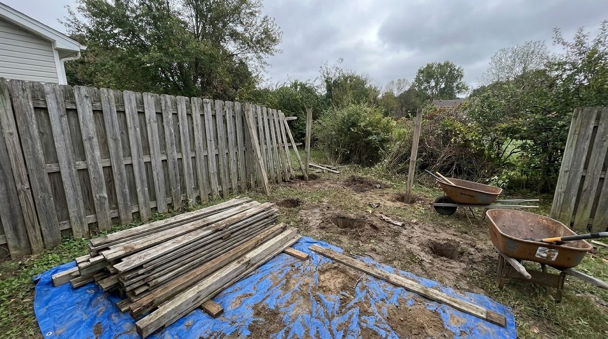 Weathered old wood fence half torn out with boards stacked for hauling away
