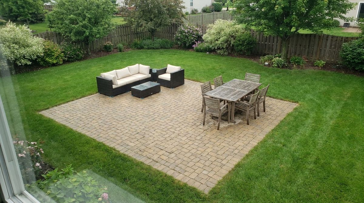 Square 20 by 20 foot concrete paver patio with seating group in a backyard