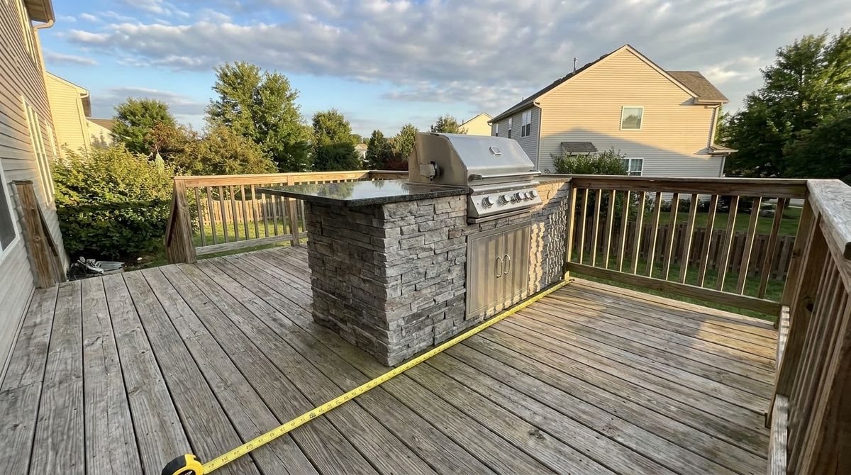 Built-in gas grill in a stone island on a deck, set well away from siding and railing