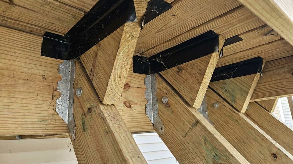 Galvanized sloped joist hangers holding deck stair stringers against the deck rim joist