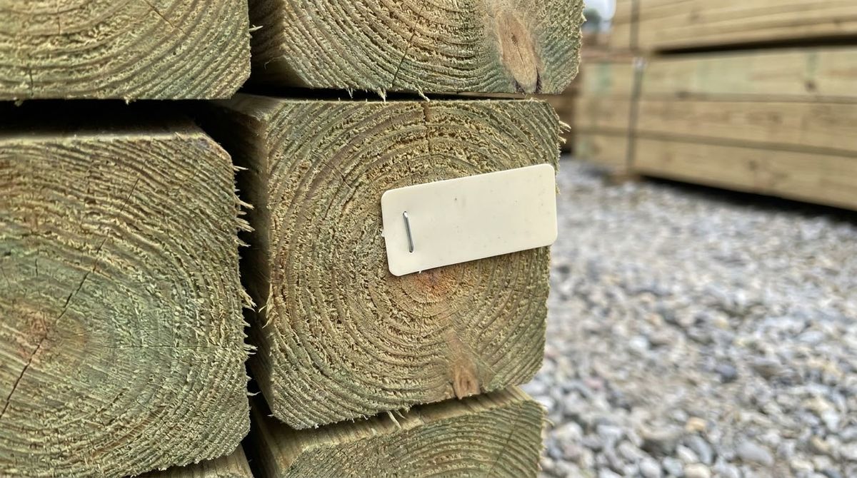 Close-up of a ground-contact treated 6x6 timber end with its plastic treatment tag
