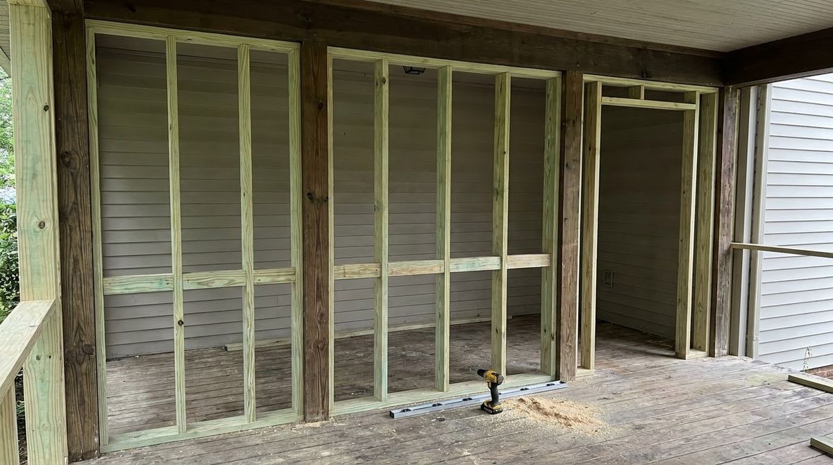 Unpainted 2x4 screen wall framing with top plate, studs and knee rails between porch posts