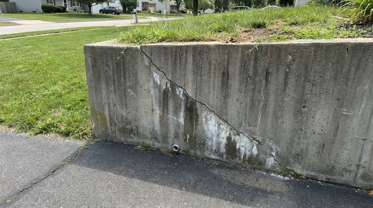 Poured concrete retaining wall with a long diagonal crack and water stains