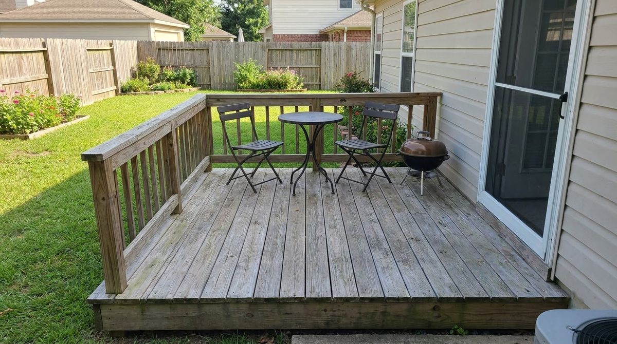 Small square wood deck with a bistro table and two chairs beside a house