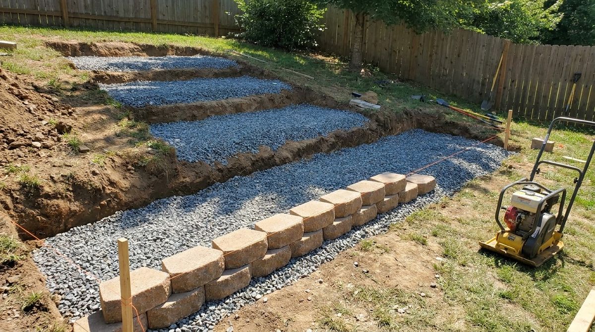 Excavated stair footprint with compacted crushed gravel base and first course of wall blocks