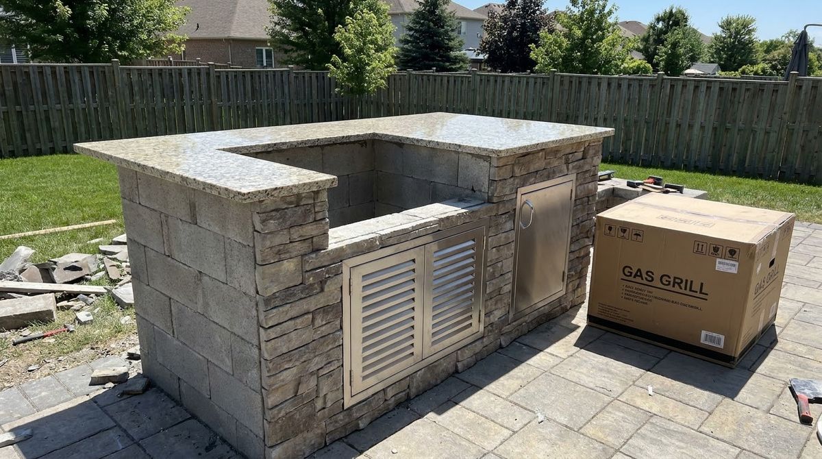 Stone outdoor kitchen island with empty grill cutout and stainless vent panels