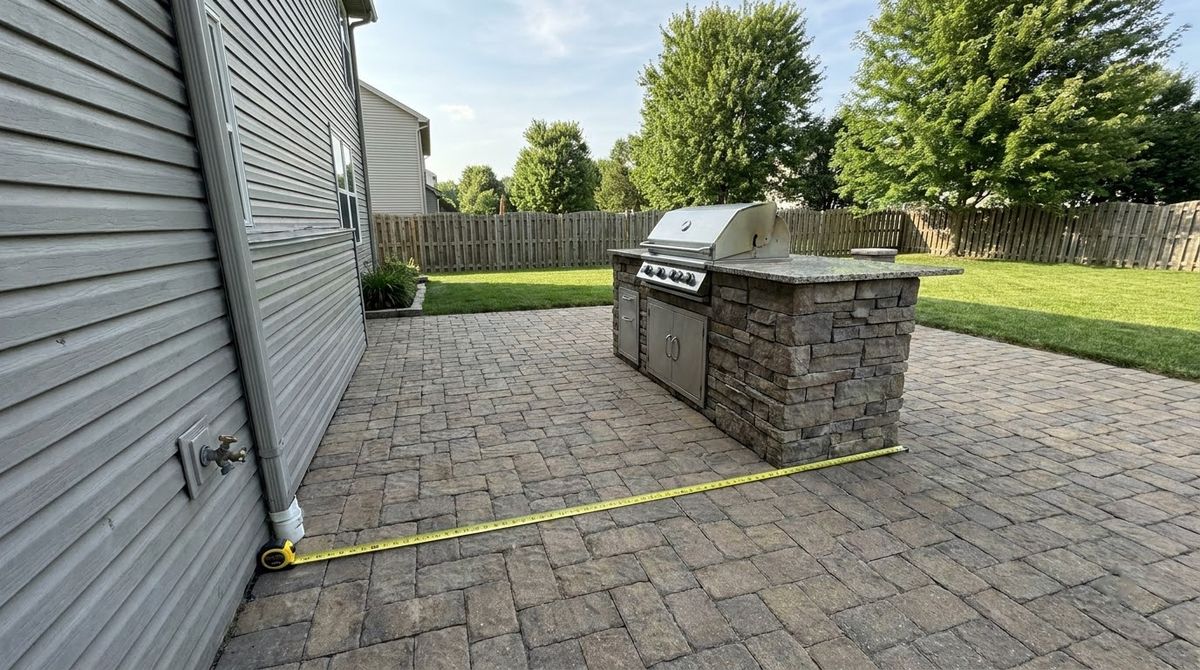 Outdoor kitchen island placed well out from the house siding on a paver patio