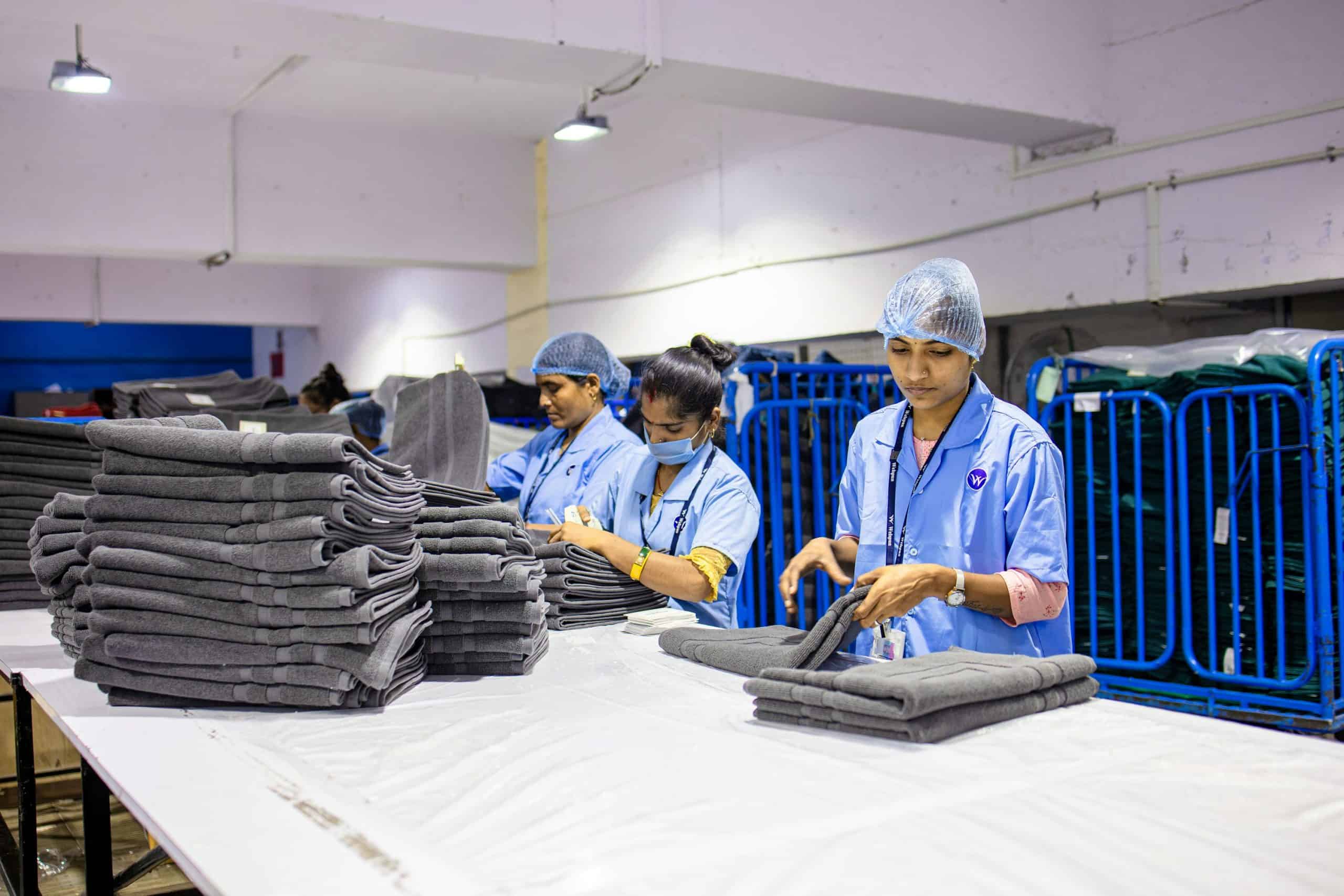 Workers fold and stack clean white towels in a professional laundry facility in Saigon
