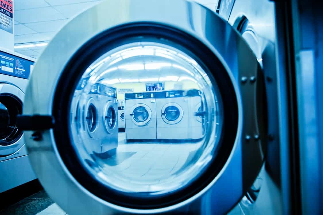 Interior of a modern laundromat with rows of steel front-load washing machines and open floor space