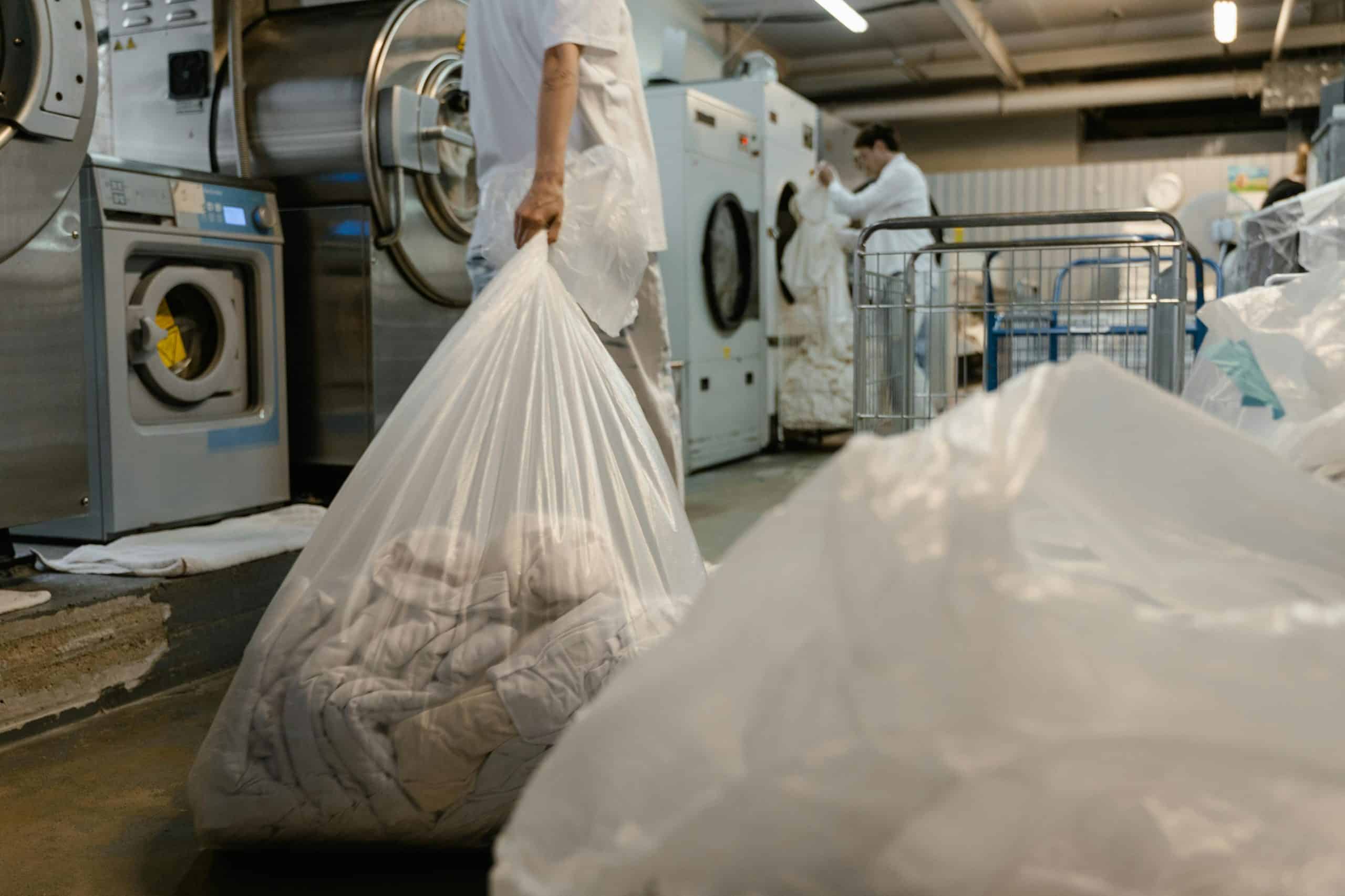 Laundry delivery worker carrying a plastic bag of clean clothes at a laundry facility in Ho Chi Minh City