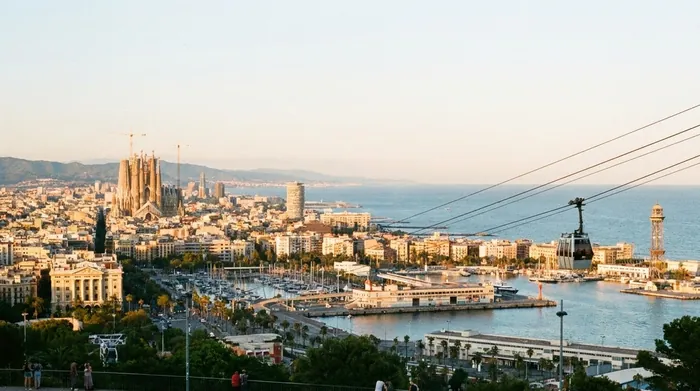 Illustration of Barcelona and its harbour seen from a hill, with a cable car