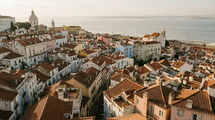 Illustration of terracotta rooftops stepping down to the Tagus in Lisbon