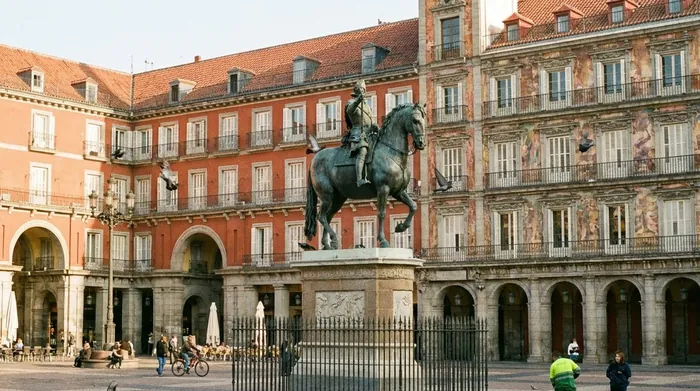 Illustration of an equestrian statue in an arcaded square in Madrid