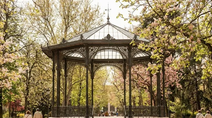 Illustration of an iron bandstand among blossoming trees in a Madrid park