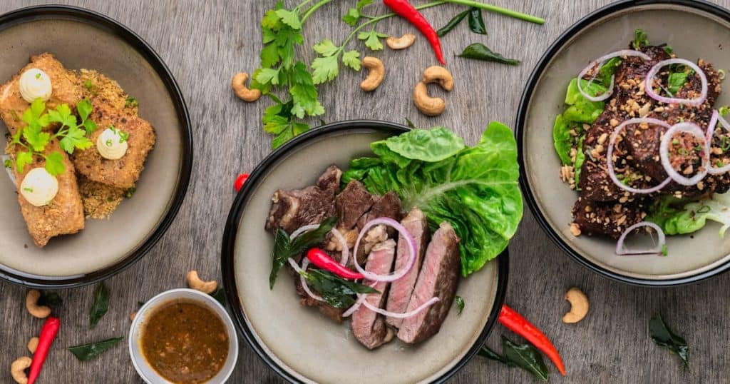 Delicious Asian beef with fresh greens and vegetables on a rustic wooden table.
