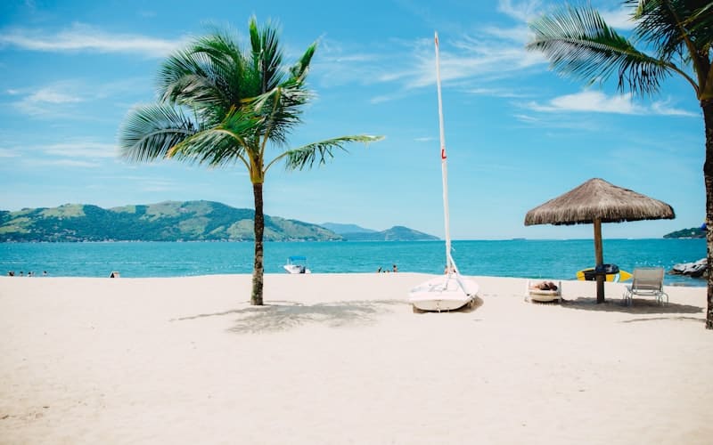 Golden sunset light illuminating a tropical beach with palm trees swaying in warm evening breeze at a Thai island resort