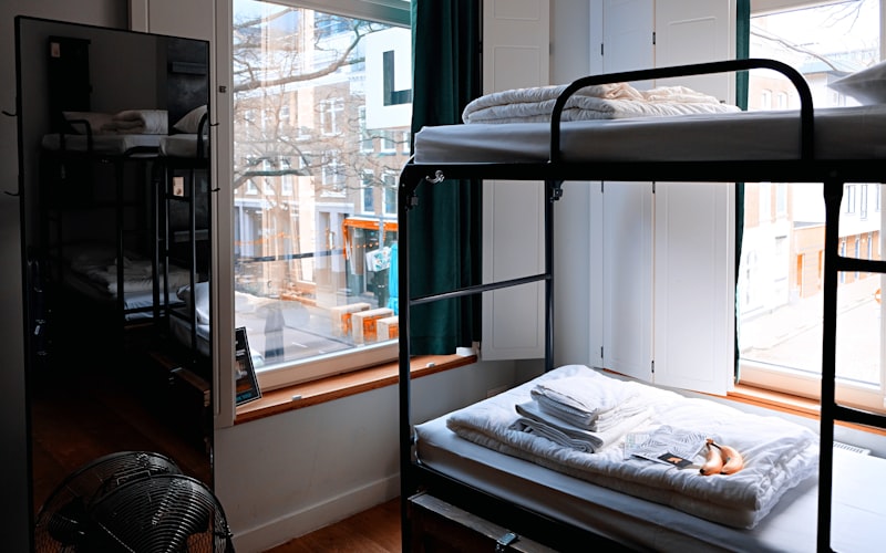 Modern capsule-style hostel dorm room with individual privacy curtains ambient lighting and clean white bedding