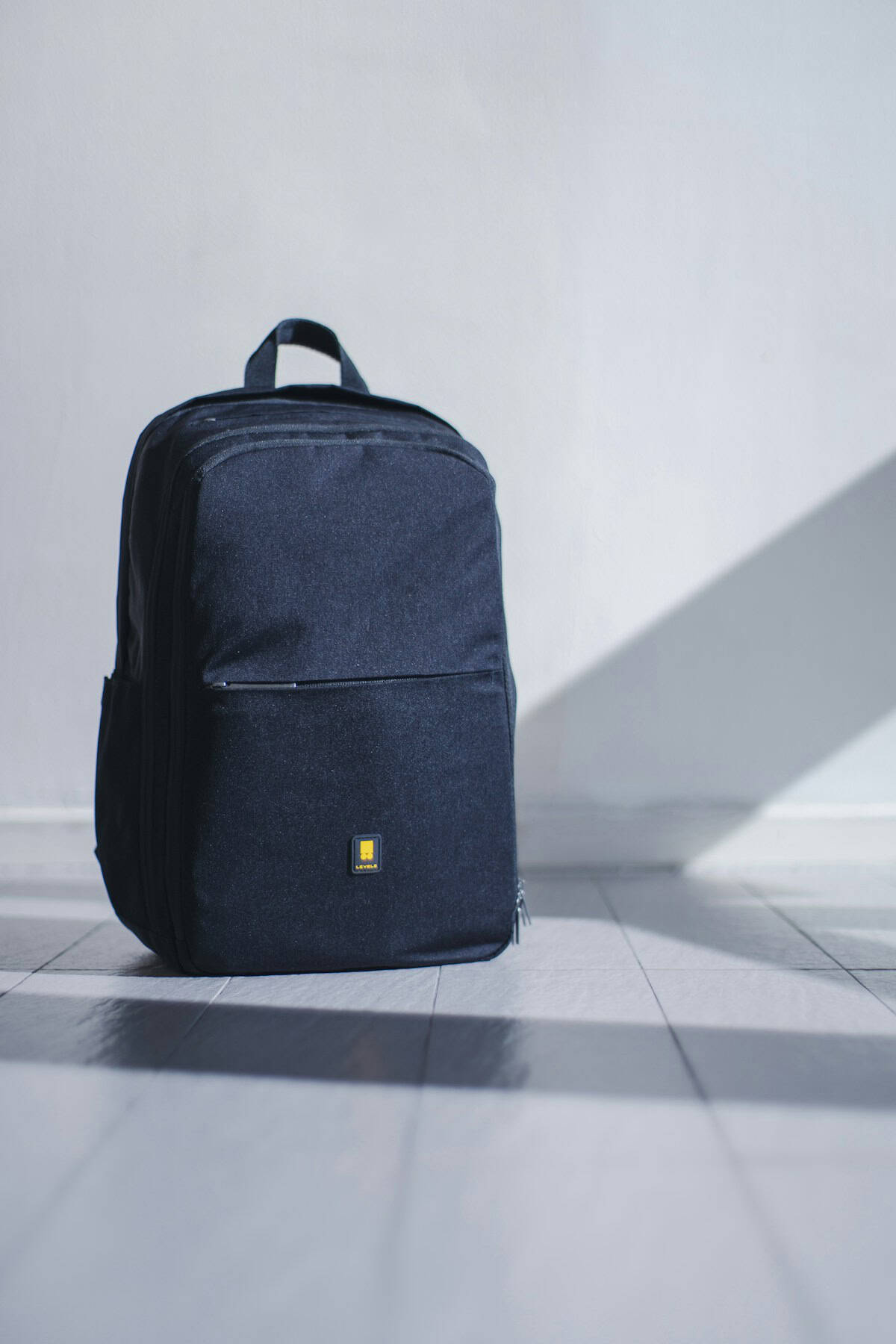 Open travel backpack with neatly folded clothes sunglasses and travel essentials laid out on a wooden floor before a tropical beach trip