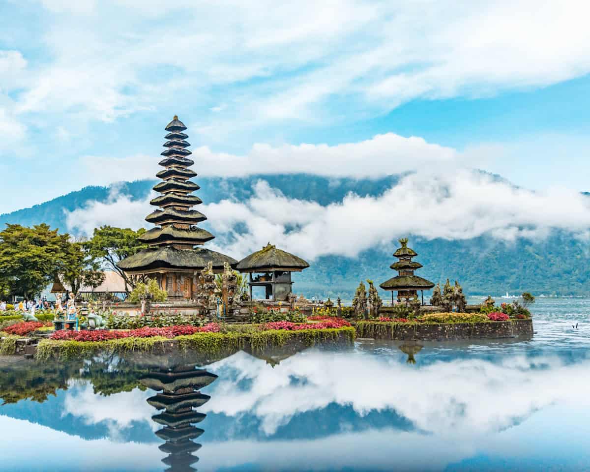 Calm blue ocean water at Amed Beach east Bali with traditional colorful jukung fishing boats resting on black volcanic sand and Mount Agung in background