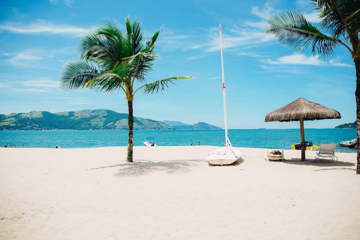 Crowded tropical beach at sunset with colorful umbrellas and beachgoers along a bustling coastline