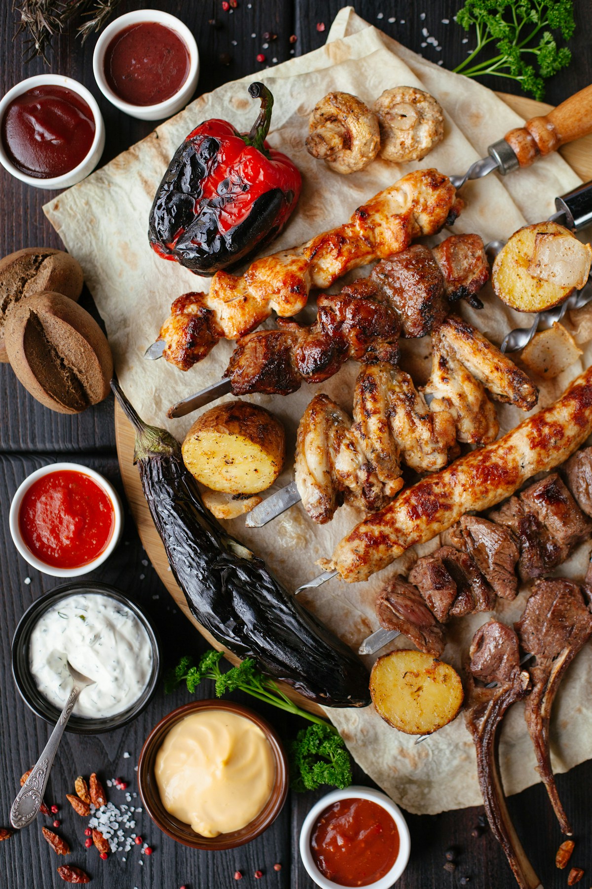 Colorful plate of nasi campur with rice surrounded by small dishes of traditional Balinese sides including sate lilit and sambal on a wooden table