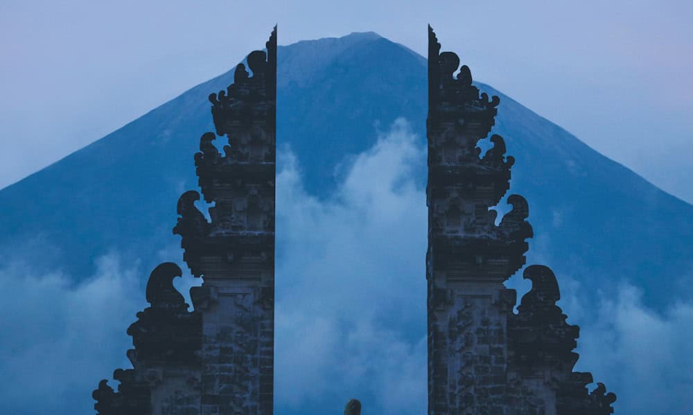 Golden sunrise illuminating the caldera of Mount Batur volcano in Bali with hikers silhouetted on the summit ridge overlooking Lake Batur