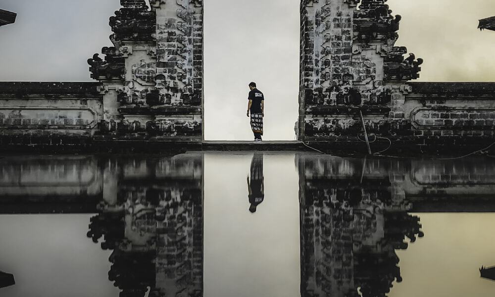 Tall tropical waterfall cascading into a natural turquoise pool surrounded by lush green jungle and moss covered rocks in Bali