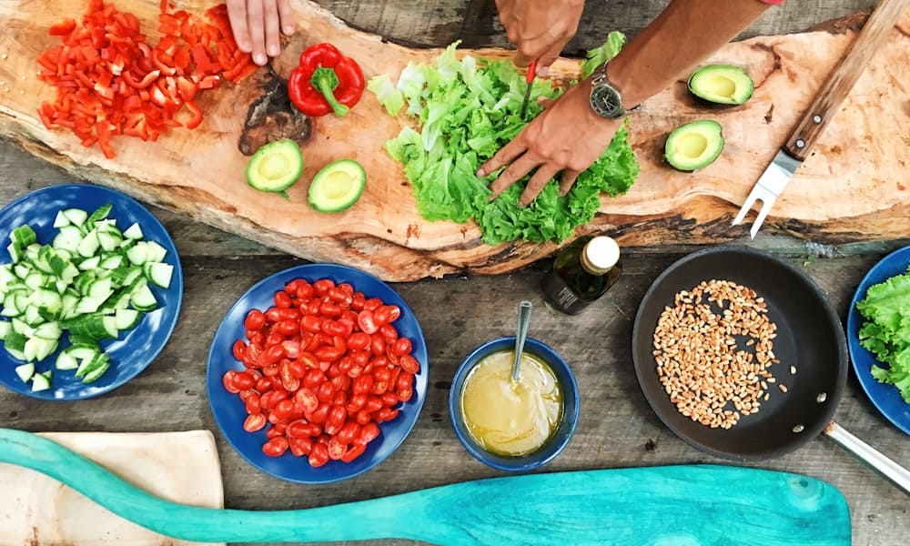 Traditional Balinese outdoor cooking class with fresh spices herbs and ingredients laid out on a wooden table surrounded by tropical plants