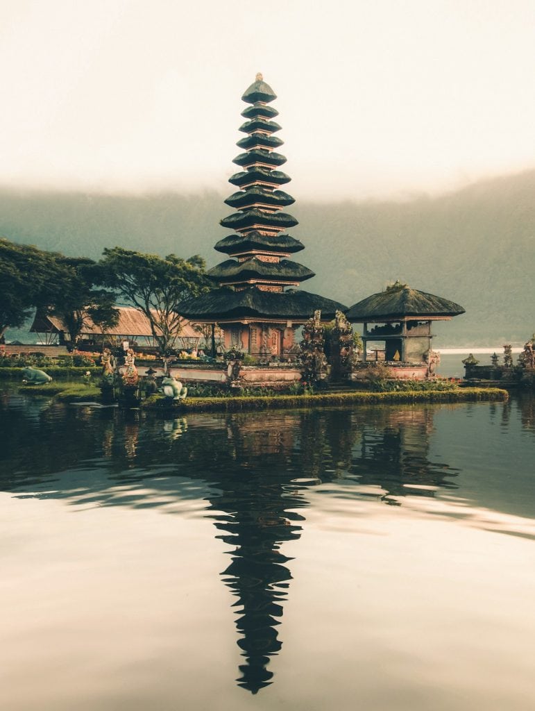 Ancient Balinese temple with tiered pagoda structure near water, showcasing traditional architecture.