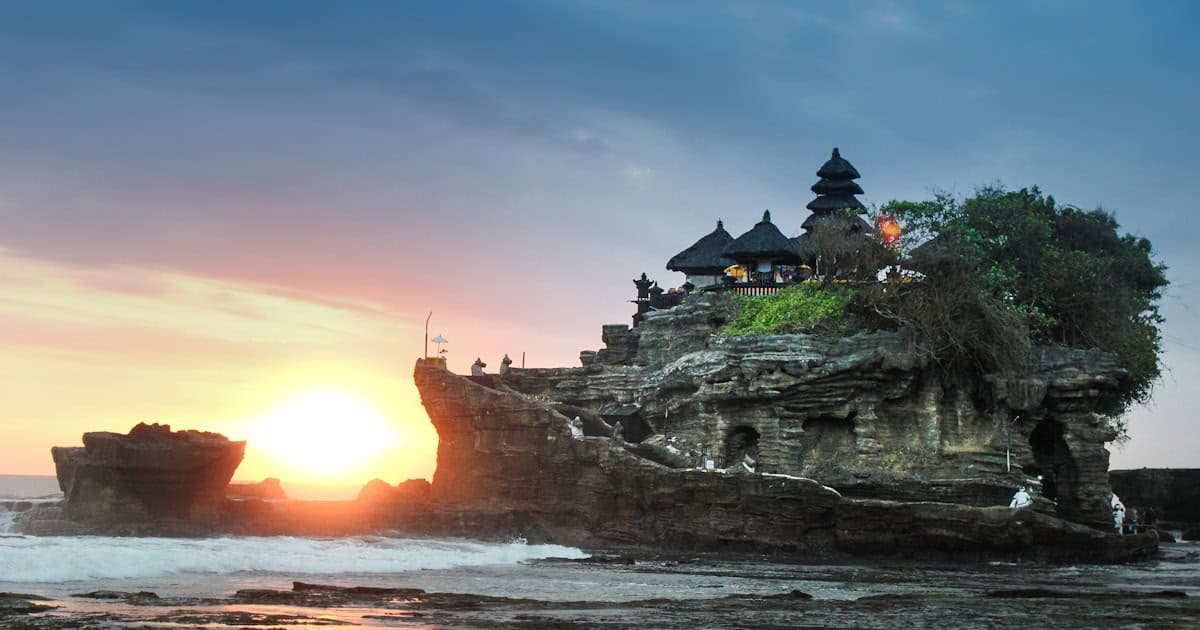 Ancient stone temple gate at Lempuyang Bali framed against golden sunset sky with Mount Agung volcano visible in the background