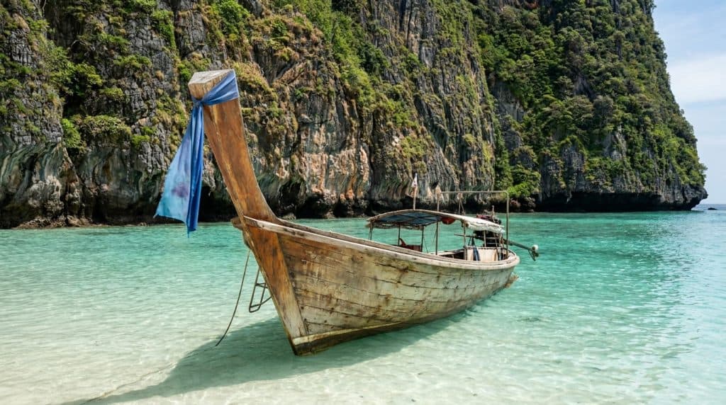Boat anchored on turquoise water near lush green cliffs.