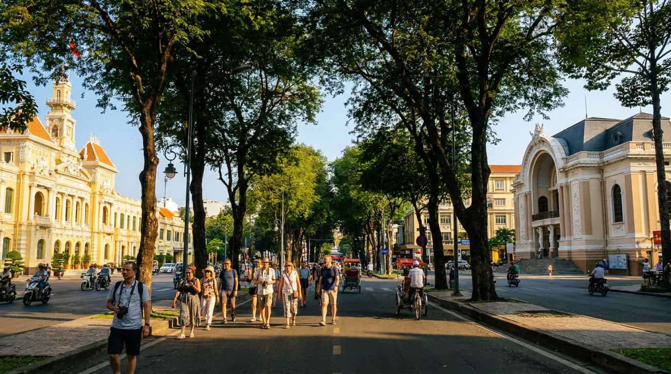 Tourists walking past French colonial buildings on a tree-lined street in District 1 Ho Chi Minh City