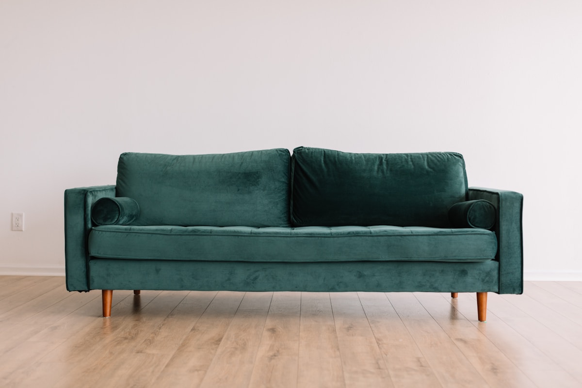 Solid walnut tapered sofa leg with brass ferrule detail on light hardwood floor — mid century modern furniture details