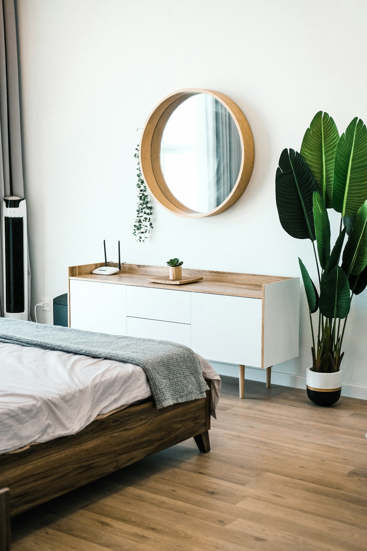 Minimalist Scandinavian shelf styled with matte ceramic vessels, a faux trailing plant, and a woven seagrass basket on a white-painted shelving unit