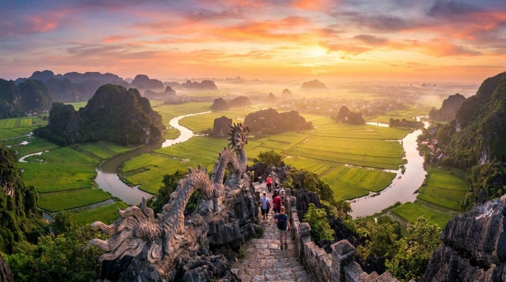 Mua Cave Ninh Binh — Panoramic sunrise view from Mua Cave Ninh Binh summit showing Tam Coc valley, karst mountains and t