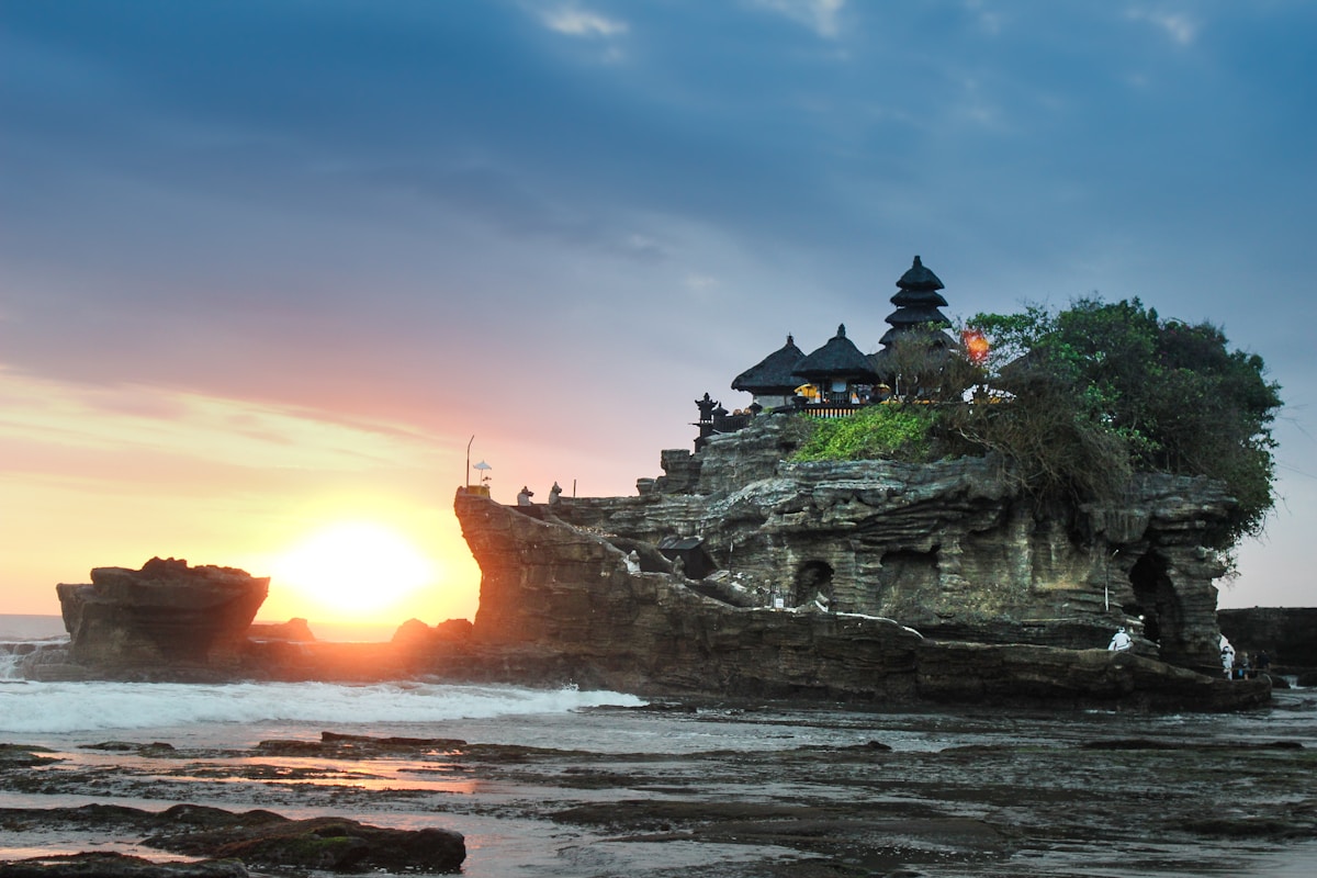 Traditional wooden boat approaching Nusa Penida island with turquoise water and dramatic cliffs