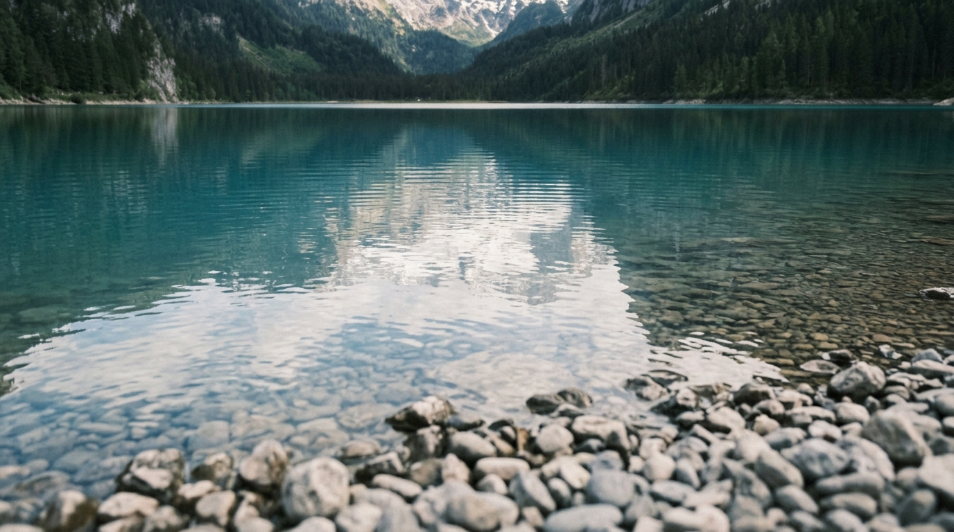Close-up of Gosausee turquoise water with Dachstein glacier and snow patches reflected in calm lake surface in best day trips from hallstatt