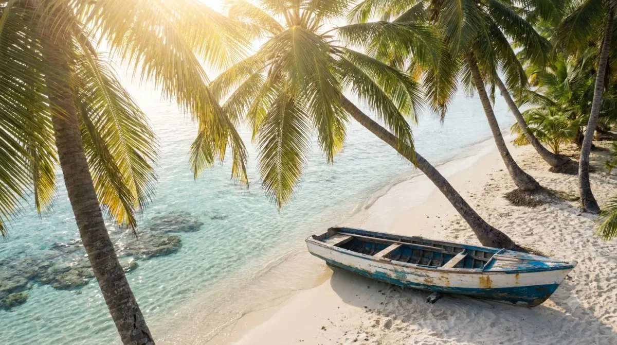 White sand Caribbean beach with leaning palms and a wooden boat on the shore