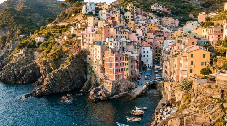 Pastel houses stacked on a cliff above a small harbour in Cinque Terre