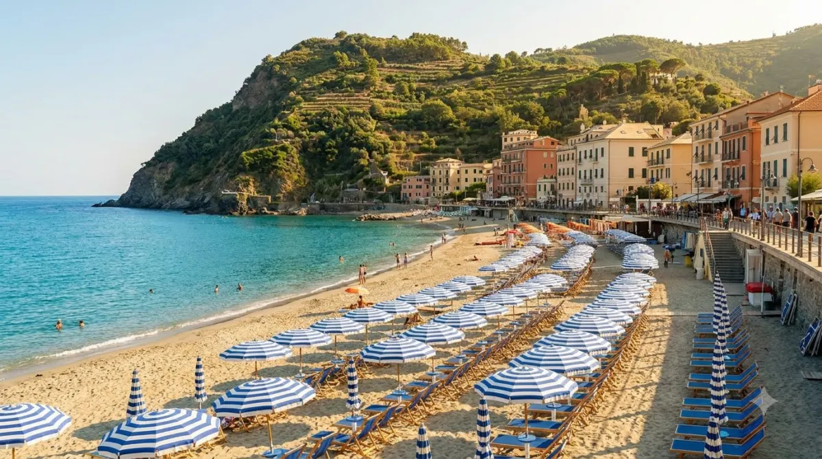 A sandy beach with striped umbrellas below a headland at Monterosso