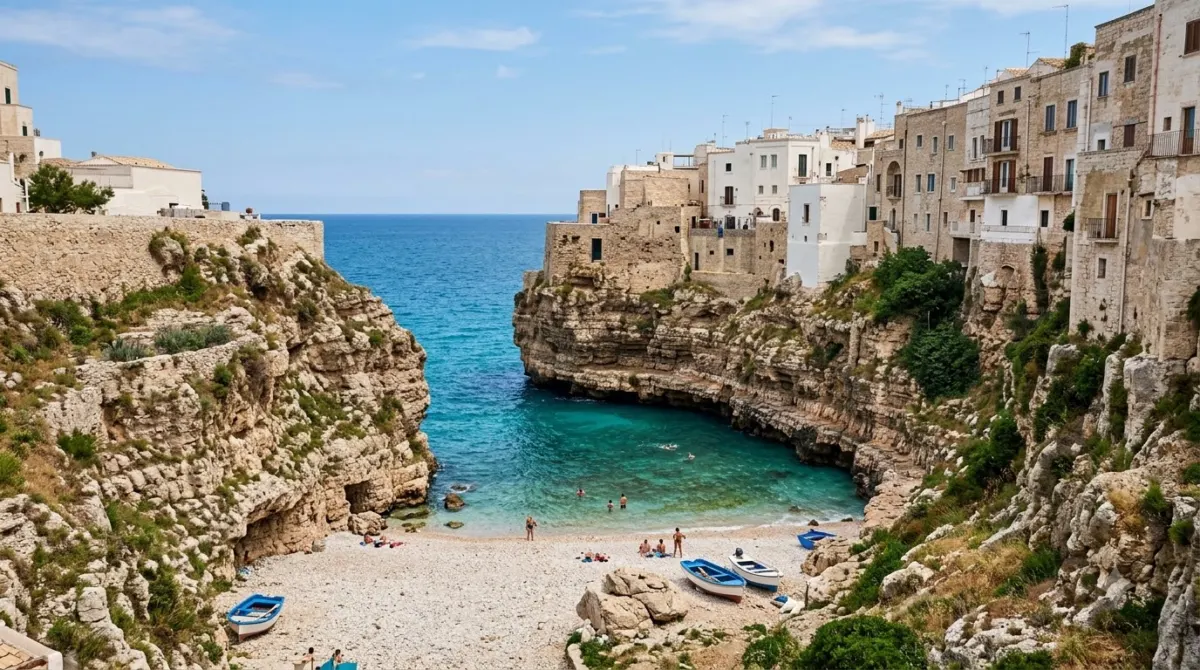 A pebble cove between limestone cliffs with houses built along the edge at Polignano a Mare