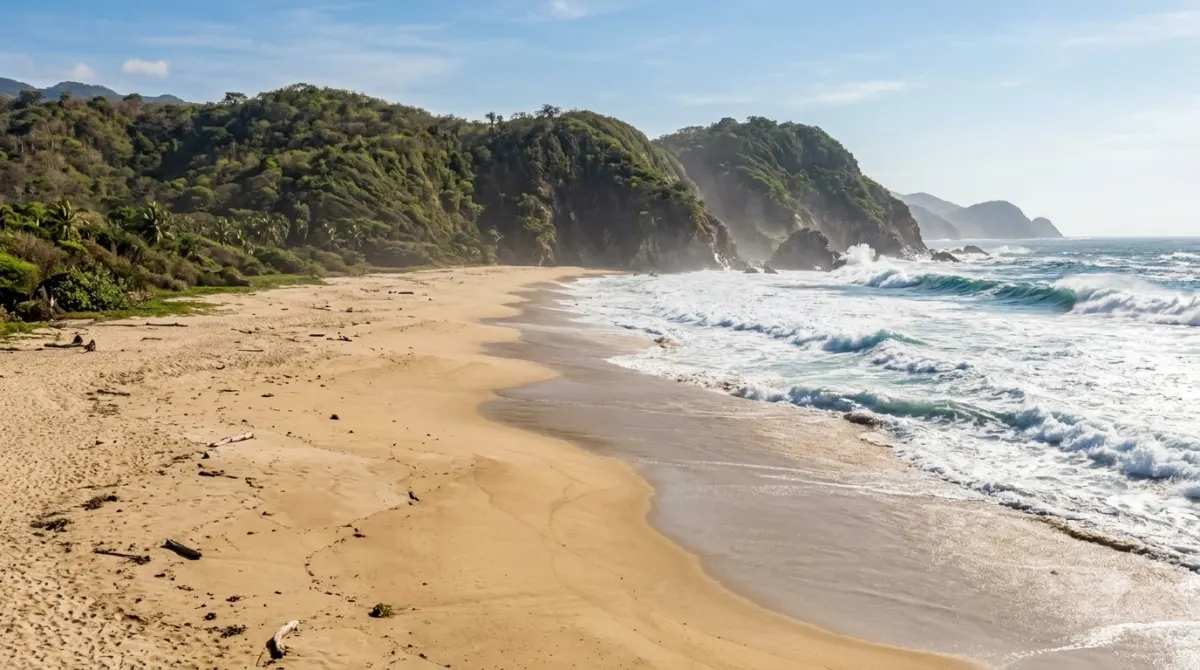 A wide empty Pacific beach with big surf and green headlands on the Oaxaca coast, Mexico