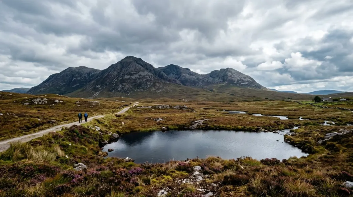 Bog and bare mountains under a wide cloudy sky with a small lake, Connemara, Ireland