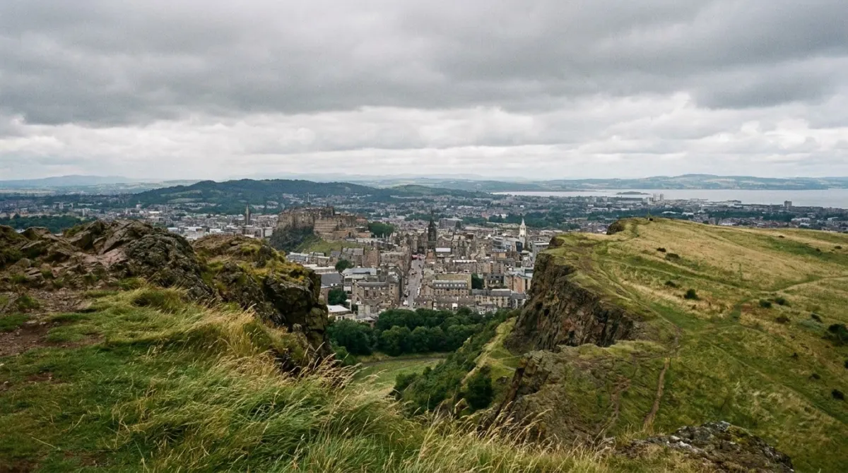 A view over a city and a firth from a grassy hilltop with rocky outcrops, Arthur's Seat, Edinburgh