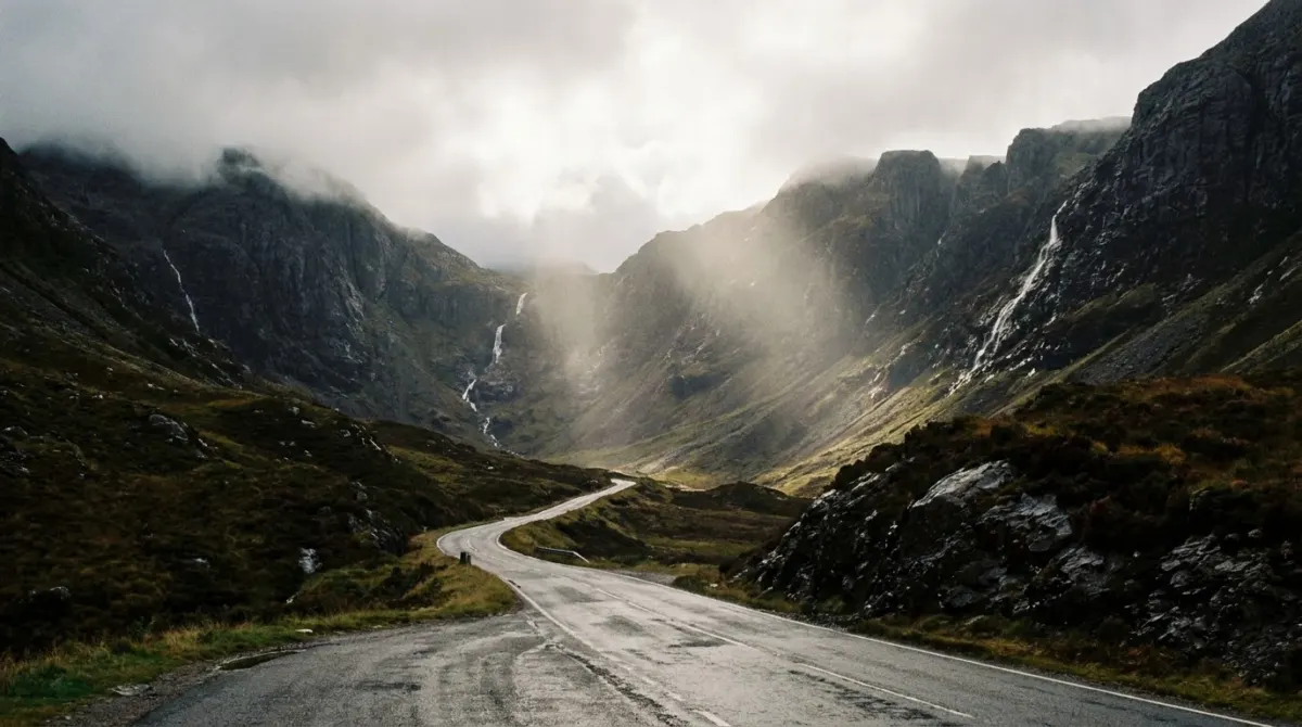 A road running through a steep sided mountain glen with waterfalls on the slopes, Glencoe, Scotland