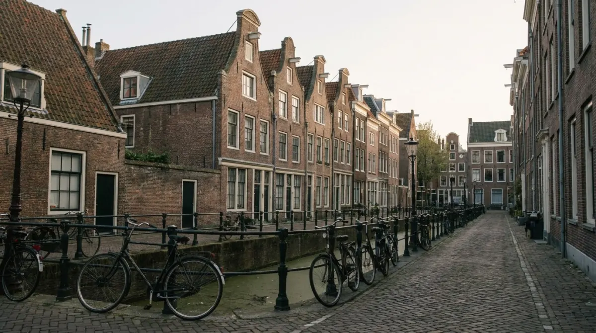A quiet narrow street of brick houses with bicycles and small shops beside a canal, Jordaan, Amsterdam