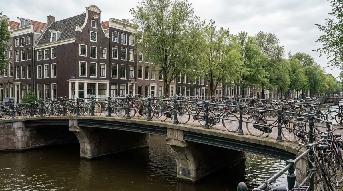 Bicycles parked along the railing of a canal bridge with gabled houses behind, Amsterdam, Netherlands