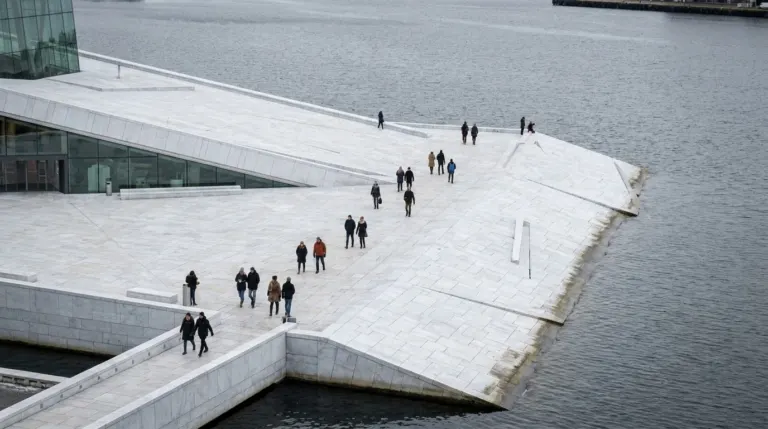 A white marble opera house with a sloping roof rising from the water, people walking on it, Oslo, Norway